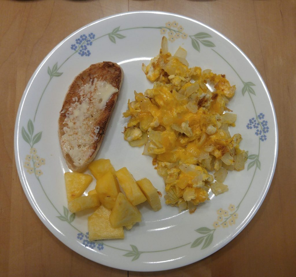 Egg, cheese and onion scramble, fresh pineapple, and ciabatta toast with butter
